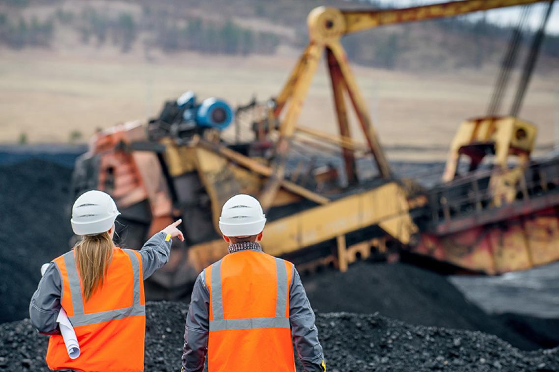 man and woman wearing Hi-vis in a quarry with a digger in background